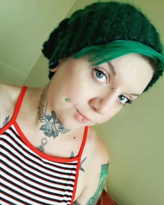  Piercing bridge et cheek sur femme aux cheveux verts 
