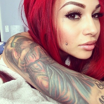  Piercing cheek, joue, fossette anneau sur femme avec le bras tatoué et les cheveux rouges 
