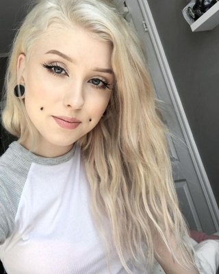  Piercing cheek, joue, fossette sur femme blonde avec un plug au lobe de l’oreille 