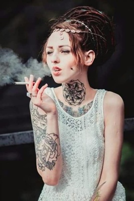  Piercing cheek, joue, fossette sur femme avec des rastas et avec des tatouages 