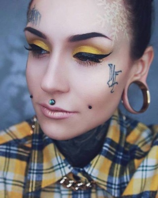  Piercing cheek, joue, fossette avec des tatouages au visage et un tunnel de grande taille au lobe de l’oreille 