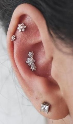  Piercing conch / conque qui représente trois fleurs et deux autres fleurs sur des piercings de l’hélix 