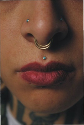  Piercing medusa doré avec un gem turquoise, un piercing au septum et deux à la narine 