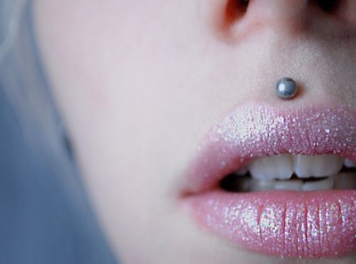  Piercing medusa boule en gros plan sur une femme avec un rouge à lèvre pailettes 
