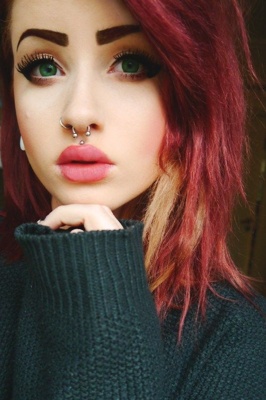  Piercing septum fer a cheval sur une femme avec des cheveux teintés en rouge 