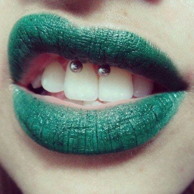 Piercing smiley / frein labial avec un fer à cheval sur femme aux lèvres vertes