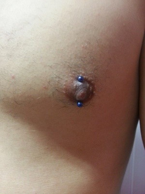  Piercing téton vertical avec une barbell bleu 